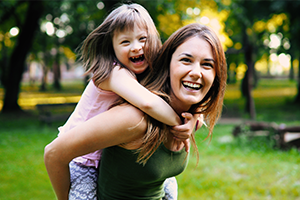 Young woman with piggy backing downs syndrome young girl smiling.