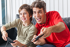 Autistic boy playing video games with pivot point staff member