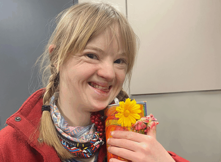 Young adult with down's syndrome smiling holding orange mug