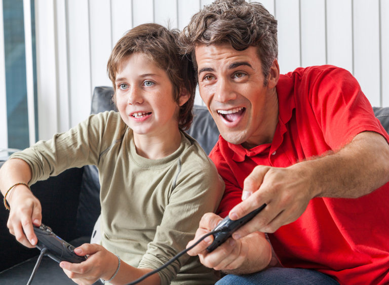 Teen boy and adult playing video games.